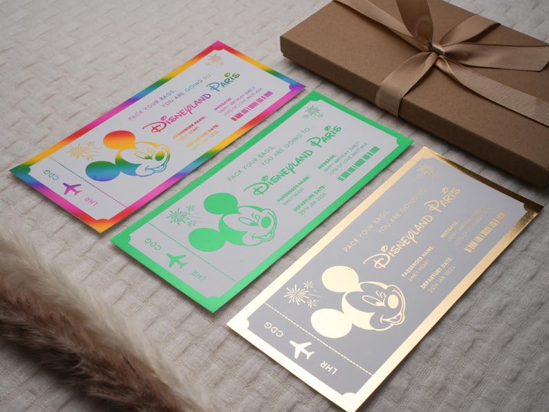 May include: Three colorful ticket-shaped invitations with a Mickey Mouse character and the text "Pack your bags, you are going to Disneyland Paris".