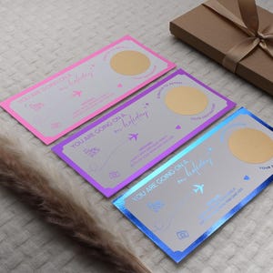May include: Three scratch-off cards with a gold foil finish. Each card has a different color background: pink, purple, and blue. The text on the cards reads "You are going on a holiday".