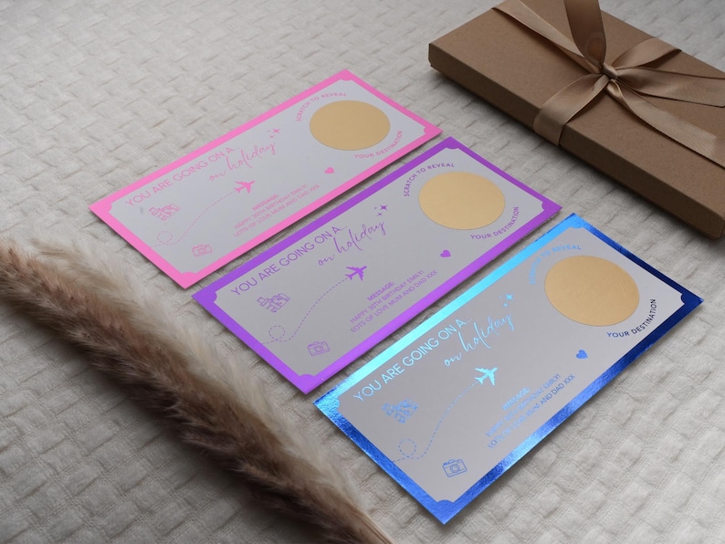 May include: Three scratch-off cards with a gold foil finish. Each card has a different color background: pink, purple, and blue. The text on the cards reads "You are going on a holiday".