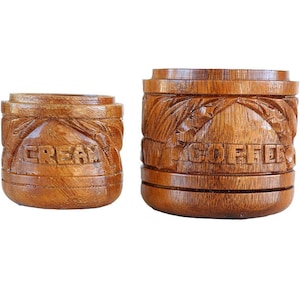 May include: Two wooden canisters with carved details. The larger canister says "COFFEE" and the smaller canister says "CREAM".