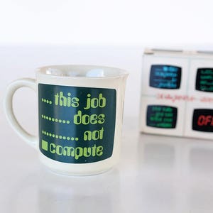 May include: White ceramic mug with a green and black design that says "...this job does not compute".