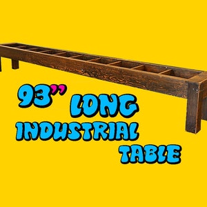 May include: A long, dark brown wooden table with a rustic finish. The table is 93 inches long and has a series of open shelves along the top.  "93" LONG INDUSTRIAL TABLE is written in blue and pink letters below the table.