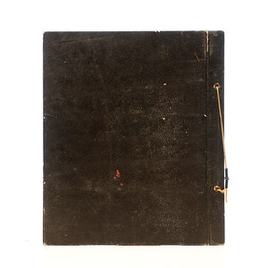 May include: A dark brown, worn, leather-bound book with a string closure. The book is closed and the spine is visible.