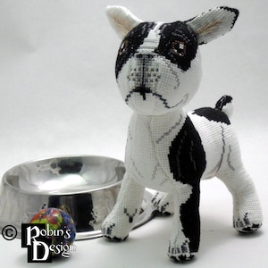 Może przedstawiać: Pluszowa zabawka w kształcie psa rasy Boston Terrier w kolorze czarno-białym z brązowym nosem i brązowymi oczami. Pies stoi na białym tle obok srebrnej miski dla psa i kolorowej piłki.