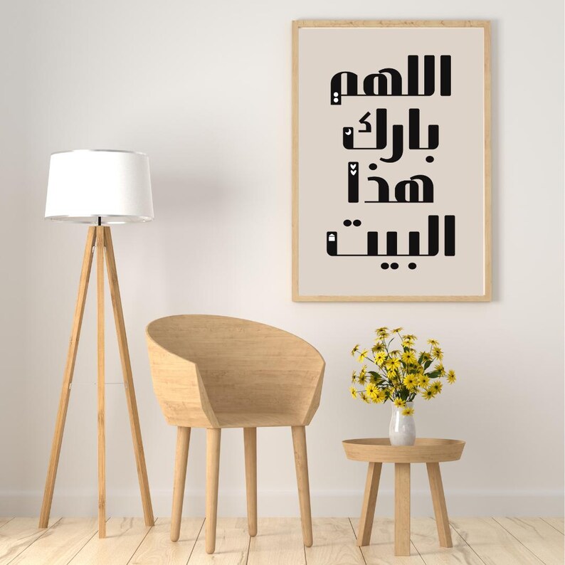Op de afbeelding: Een moderne woonkamer met een houten staande lamp met een witte lampenkap, een gebogen houten stoel en een kleine ronde bijzettafel. Een ingelijste print met Arabische kalligrafie hangt aan de muur. Een vaas met gele bloemen staat op de tafel.