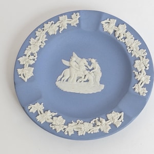 May include: A blue and white ceramic ashtray with a white grapevine border and a white relief image of a mythological scene.