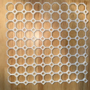 May include: White plastic grid with a repeating octagonal pattern. The grid is made of a series of connected octagons with small circles in the center of each octagon.
