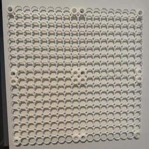 May include: White plastic grid with a hexagonal pattern and small white screws at the corners and in the center.