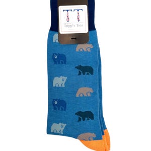 May include: Blue socks with a pattern of bears in different shades of blue, grey, and brown. The socks have an orange cuff and a tag that says "Tripp's Ties" with two stylised ties.