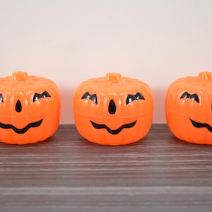May include: Three orange plastic jack-o'-lantern containers with black painted faces.