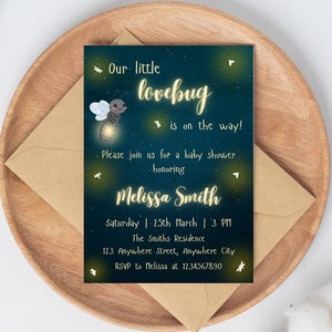 Könnte beinhalten: Eine Babyparty-Einladung mit marineblauem Hintergrund und einem skurrilen Design. Der Text lautet "Our little lovebug is on the way!" mit dem Namen Melissa Smith und Veranstaltungsdetails. Die Einladung liegt auf einem Holztablett mit einem Kraftpapierumschlag.