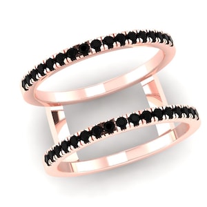 Puede incluir: Dos anillos de oro rosa con una fila de piedras negras. Los anillos están conectados por barras verticales de oro rosa, creando un efecto de doble banda. Fondo blanco.