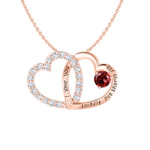 May include: Rose gold necklace with two intertwined heart pendants. One heart is set with small, clear crystals, the other with a round, red gemstone. The words "I love you" and "forever always and" are inscribed on the hearts.