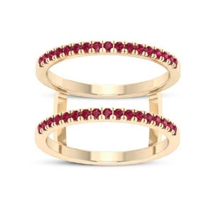 Pu&ograve; includere: Due anelli color oro, ciascuno adornato con una fila di piccole e vivaci pietre preziose rosse. Gli anelli sono impilati, creando un effetto a strati. Le pietre preziose sono uniformemente distanziate, aggiungendo un tocco di eleganza.