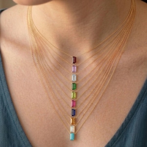 Puede incluir: Una colección de diez delicados collares de oro, cada uno con una piedra preciosa rectangular de corte baguette en un color diferente, incluyendo rojo oscuro, lavanda, azul claro, verde, lima, rosa, azul oscuro, ámbar, blanco y turquesa.
