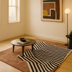 May include: A modern living room scene featuring a brown rug, a black and white striped rug, a round wooden coffee table, and a framed abstract artwork. A floor lamp with a spherical shade and a small side table are also present.