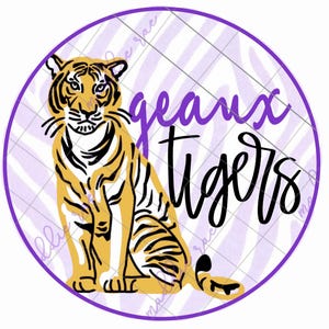 May include: A purple and white striped circle with a tiger sitting in the center. The text "Geaux Tigers" is written in black cursive.