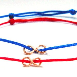 Puede incluir: Dos pulseras de la amistad con cordones rojos y azules y un dije de infinito dorado.