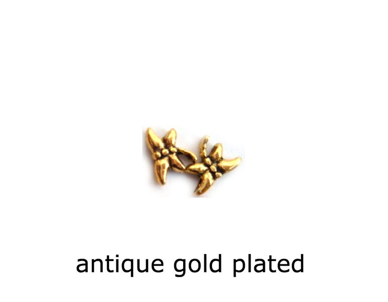 May include: Two antique gold-plated flower charms. The flowers are stylized and have five petals.