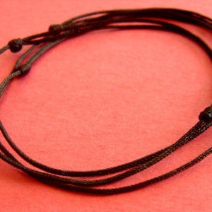 Peut inclure: Un ensemble de quatre bracelets en cordon noir avec des accents noués.