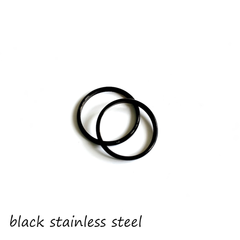 May include: Two black stainless steel rings, one slightly larger than the other, are interlocked.