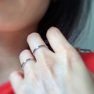 May include: Two silver rings on a person's finger. The rings are simple and plain.