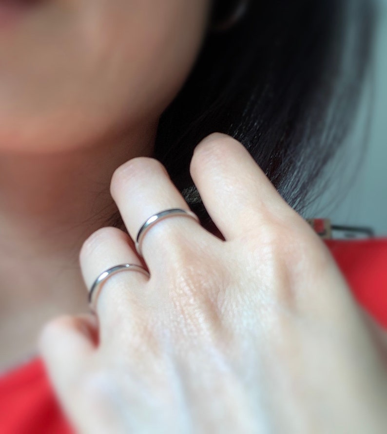 May include: Two silver rings on a person's finger. The rings are simple and plain.