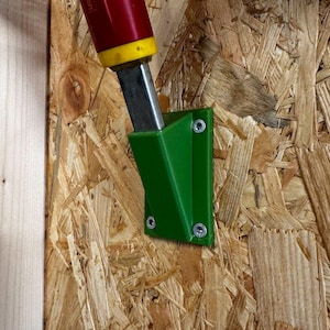 May include: A green plastic wall mount with two screws, holding a red and yellow gardening tool with the text "Wolf Garten" on the side.