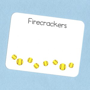 May include: White card with the text "Firecrackers" printed in black at the top. The card is decorated with a row of yellow and red softball stickers.