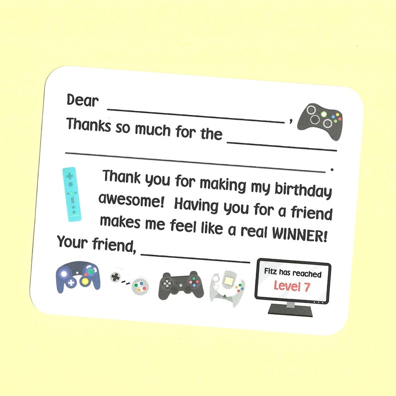 May include: A thank you card with a video game theme. The card has a blank space for the recipient's name and a space to write a message. The card also features a variety of video game controllers, including a Nintendo Wii remote, a PlayStation controller, a GameCube controller, and a Sega Genesis controller. The card also includes a computer screen with the text "Fitz has reached Level 7".