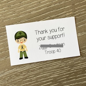 May include: Thank you for your support! Ziggy Goodman Troop 40. Illustration of a boy scout wearing a green hat, glasses, and a scout uniform.