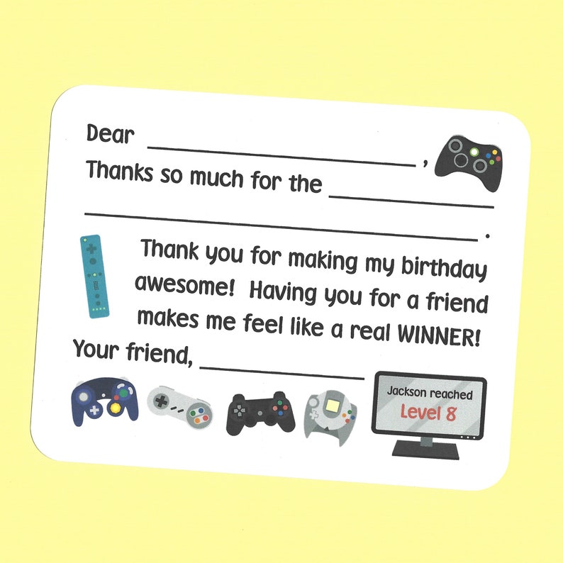 May include: A thank you card with a video game theme. The card has a blank space for the recipient's name and a space to write a message. The card also features a variety of video game controllers and a screen displaying the text "Jackson reached Level 8".