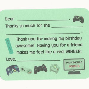 May include: A green thank you card with a video game theme. The card has a blank space for a name, a space for a gift, and a space for a signature. The card says "Dear ____, Thanks so much for the ____. Thank you for making my birthday awesome! Having you for a friend makes me feel like a real WINNER! Love, _____. You reached Level 6."