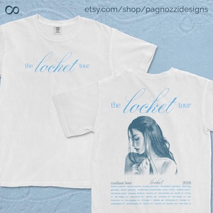 Könnte beinhalten: Weiße T-Shirts mit dem Schriftzug "the locket tour" in hellblauer Schrift. Ein Shirt zeigt die Vorderseite und das andere die Rückseite mit einem Porträt einer Frau und Tourdaten. Die Shirts sind wahrscheinlich für ein Konzert.