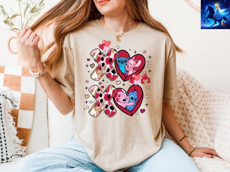 K&ouml;nnte beinhalten: Beiges T-Shirt mit einem Valentinstags-Design. Das Design umfasst zwei gro&szlig;e "XO"-Formen mit einem rosa und braunen Muster und zwei rote Herzformen mit Cartoon-Figuren. Zus&auml;tzliche Herzen, Sterne und ein Schloss sind ebenfalls enthalten.