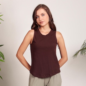 May include: A brown sleeveless tank top with a scoop neck. The tank top is made of a soft, comfortable fabric and has a relaxed fit.