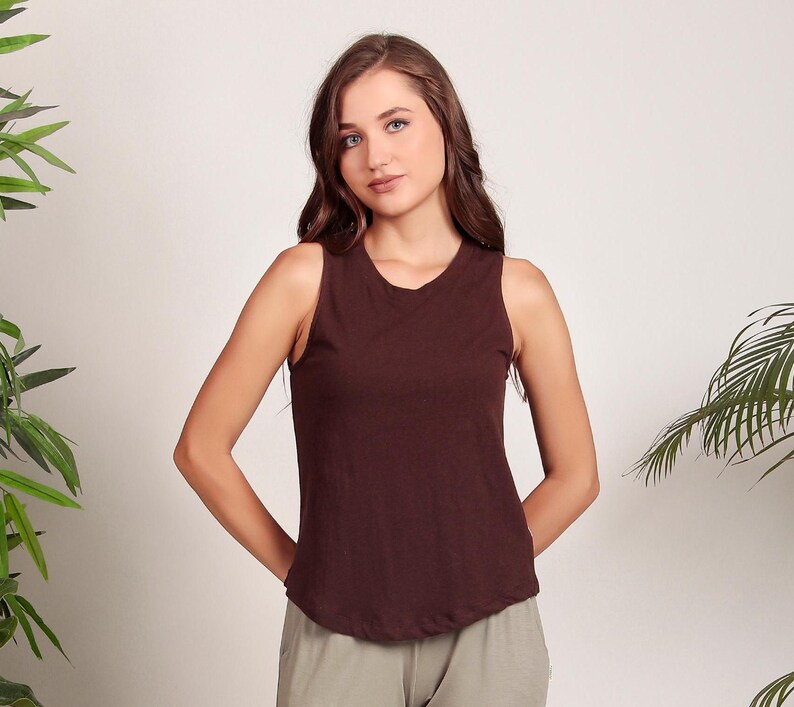 May include: A brown sleeveless tank top with a scoop neck. The tank top is made of a soft, comfortable fabric and has a relaxed fit.