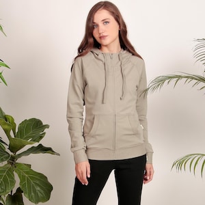 Puede incluir: Una sudadera gris claro con cremallera, capucha y cord&oacute;n. La sudadera tiene un bolsillo delantero y mangas largas.