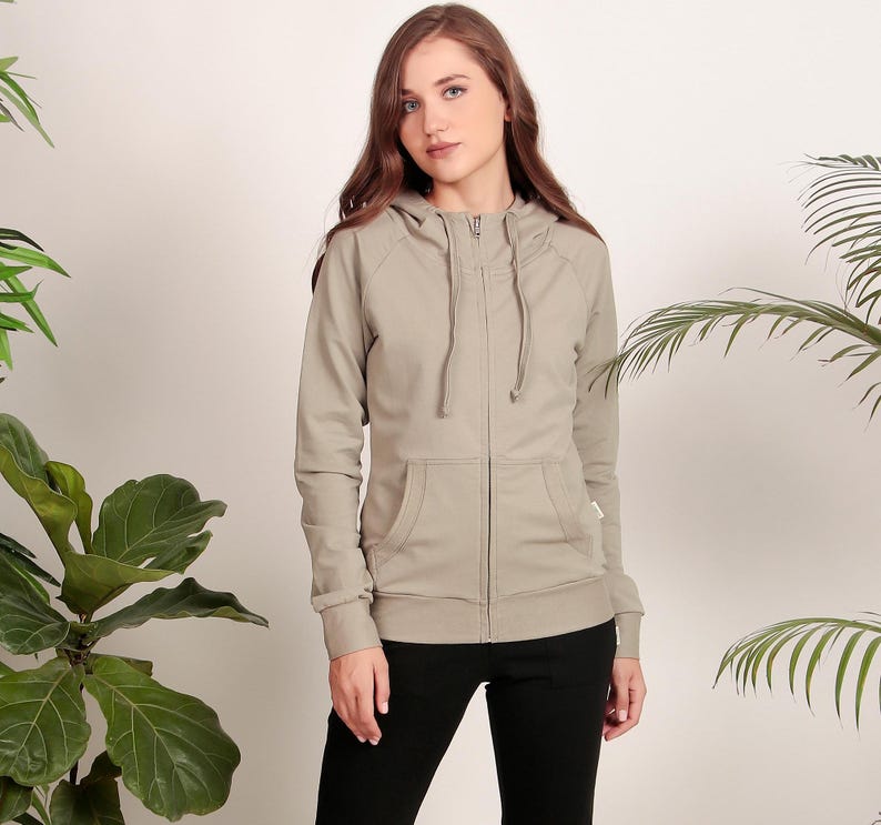 Puede incluir: Una sudadera gris claro con cremallera, capucha y cord&oacute;n. La sudadera tiene un bolsillo delantero y mangas largas.