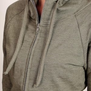 Puede incluir: Una sudadera con capucha verde con cierre de cremallera y capucha con cord&oacute;n.