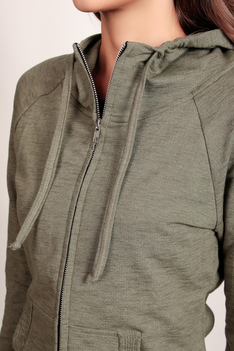 Puede incluir: Una sudadera con capucha verde con cierre de cremallera y capucha con cord&oacute;n.