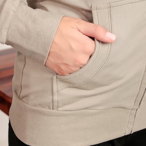 Puede incluir: Una sudadera con capucha de color marr&oacute;n claro con cierre de cremallera y un bolsillo delantero. La sudadera tiene un corte holgado y est&aacute; hecha de un tejido suave y c&oacute;modo.