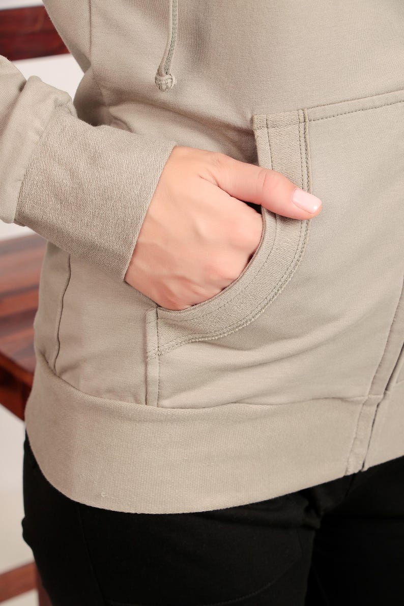 Puede incluir: Una sudadera con capucha de color marr&oacute;n claro con cierre de cremallera y un bolsillo delantero. La sudadera tiene un corte holgado y est&aacute; hecha de un tejido suave y c&oacute;modo.