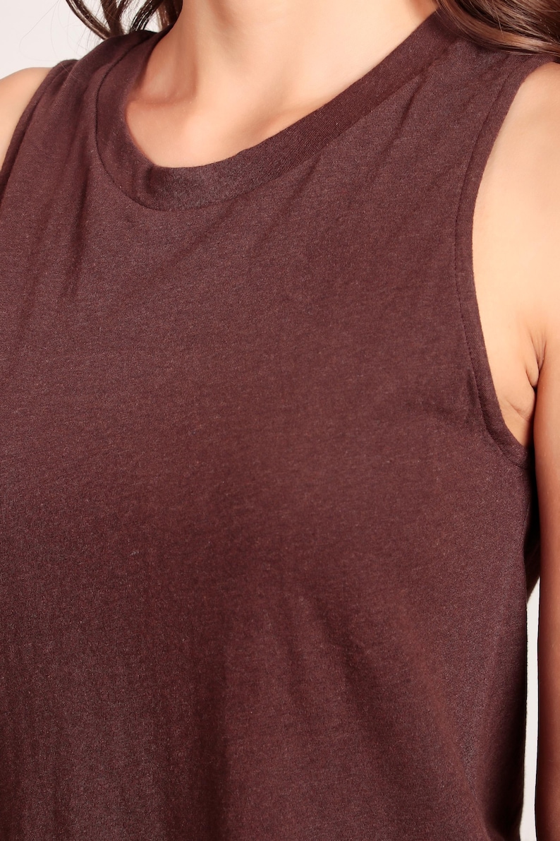 May include: A sleeveless, brown tank top made of a soft, textured fabric. The top has a round neckline and a relaxed fit.