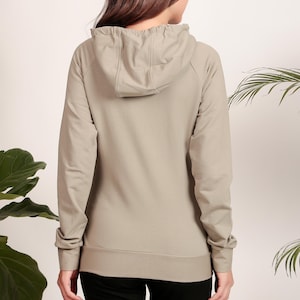 Puede incluir: Una sudadera con capucha de color gris claro con cord&oacute;n de ajuste. La sudadera tiene un corte holgado y mangas largas.