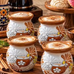 May include: Four round ceramic mugs with a white base and brown floral patterns, each filled with a frothy coffee beverage topped with cinnamon. The mugs feature a wide rim and a bulbous body, arranged on a wooden board with coffee beans.
