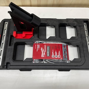 May include: A black Milwaukee Packout organizer tray with multiple compartments and a red Milwaukee Packout Most Compact label. The tray has a black metal rail on the side and a black plastic stand with a red base.