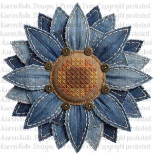 May include: A denim flower with frayed edges and visible stitching. The petals are various shades of blue denim, surrounding a centre of tan fabric with a cross-stitch design. Brown buttons are evenly spaced around the centre.
