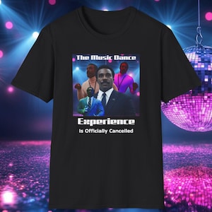 May include: Black t-shirt with a graphic of four men in a colorful, neon-lit setting. The text "The Music Dance Experience Is Officially Cancelled" is printed on the shirt.