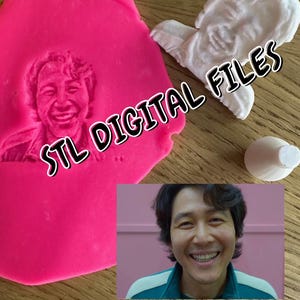 Puede incluir: Un molde de silicona rosa con una impresión 3D de la cara de una persona. El molde está al lado de un objeto blanco impreso en 3D y una base blanca impresa en 3D. El texto "STL DIGITAL FILES" está superpuesto en la imagen.